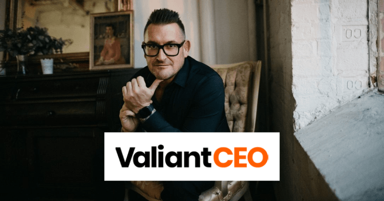 A man in glasses sits indoors with his hand on his chin. The ValiantCEO logo is displayed prominently in the foreground.