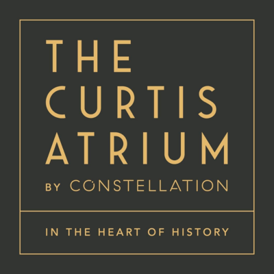 Gold text on a black background reads: “The Curtis Atrium by Constellation. In the heart of history.” Geometric, modern font style.