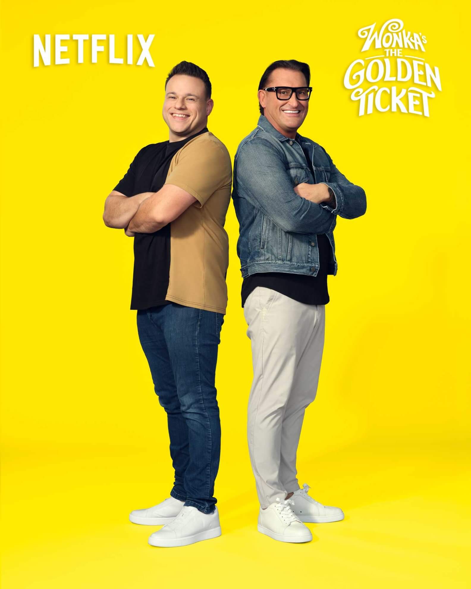 Two men stand back to back, smiling, in front of a bright yellow background with Netflix and Wonka’s The Golden Ticket logos.